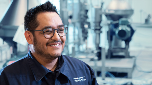 Service man posing in front of separators smiling 640x360