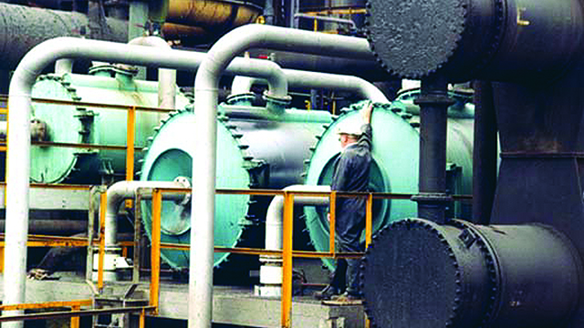Man infront of three installed Alfa Laval welded spiral heat exchangers